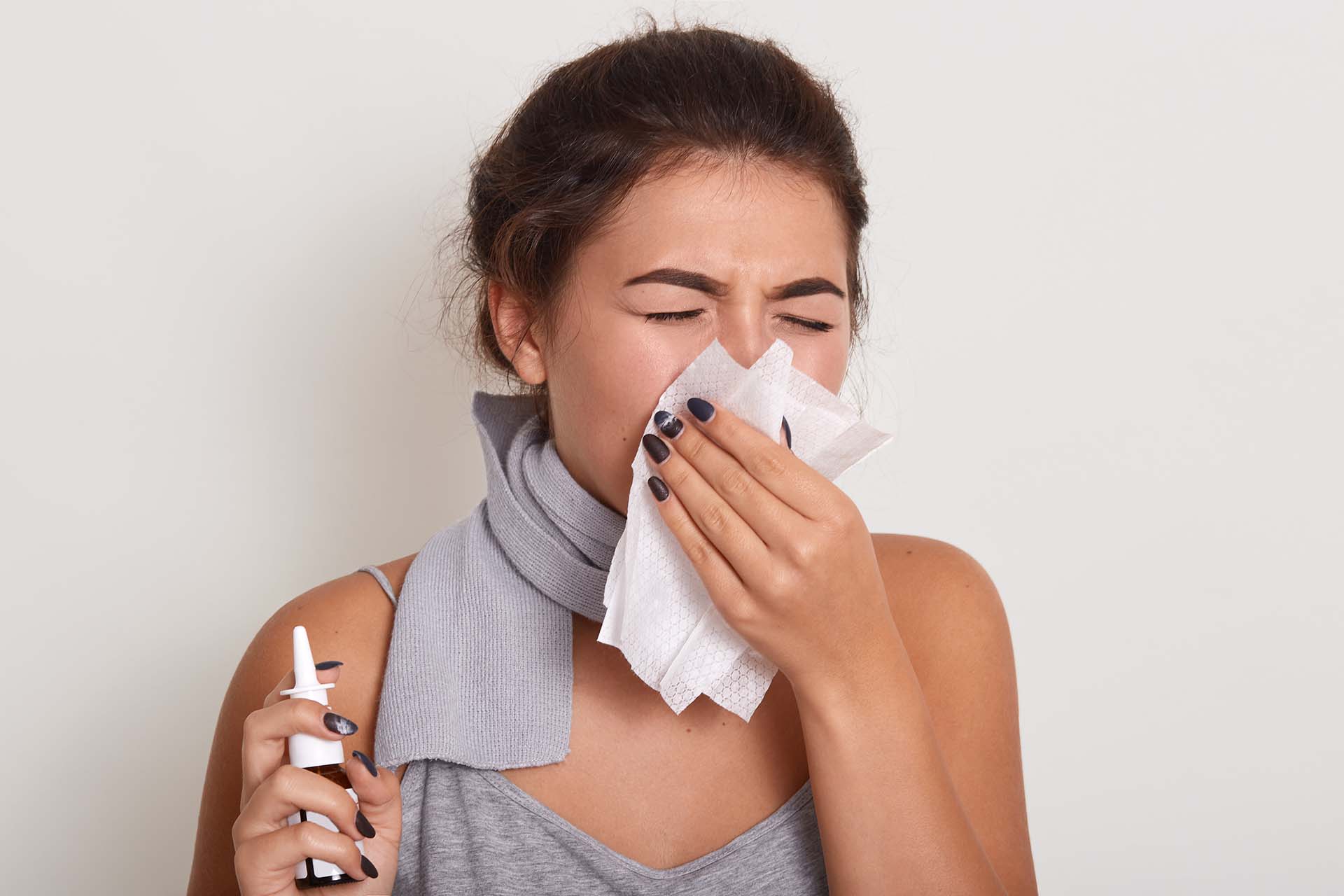 Jeune femme avec le nez bouché administre du spray nasal