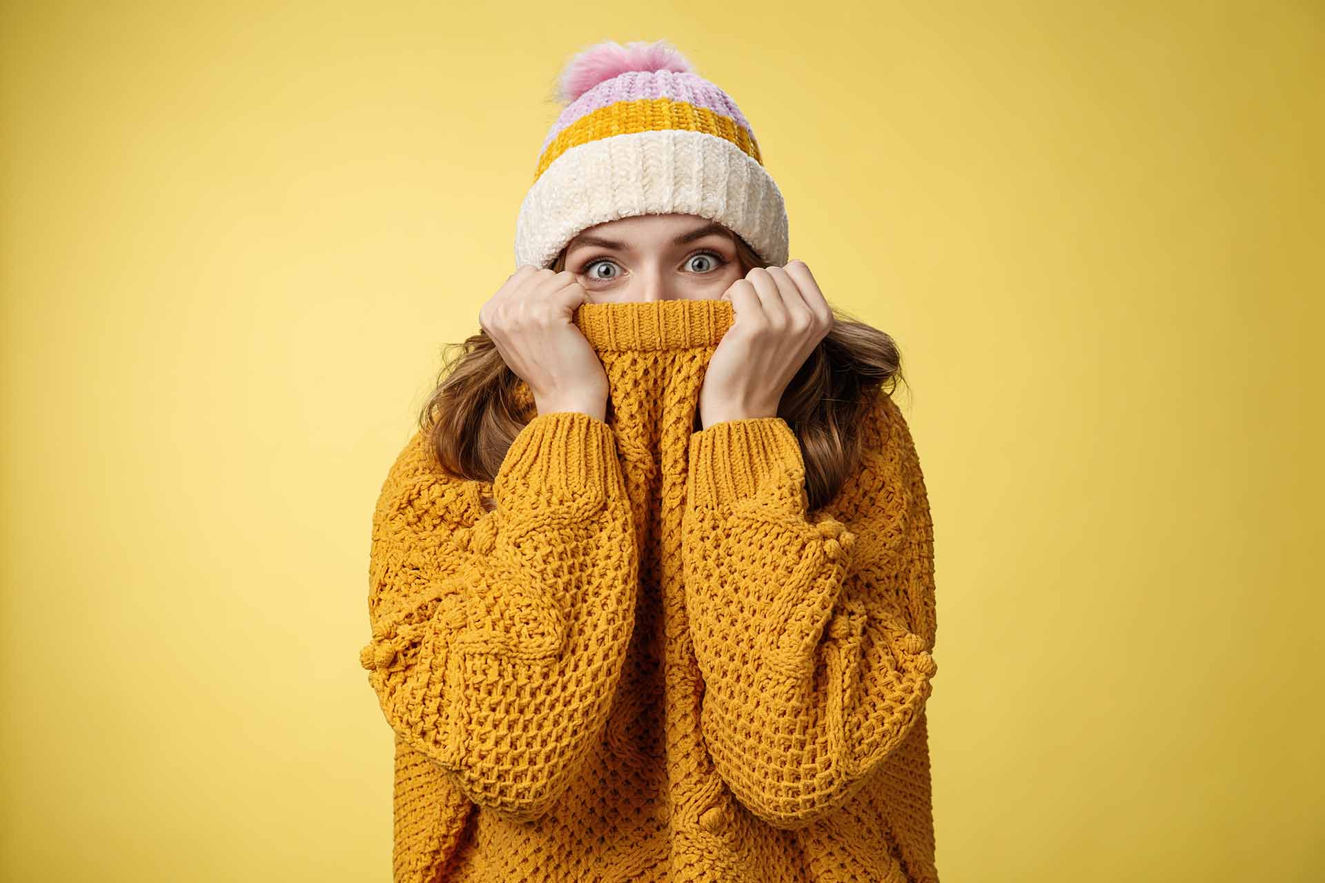 Femme au chapeau et le pull tiré sur le nez souffre du froid